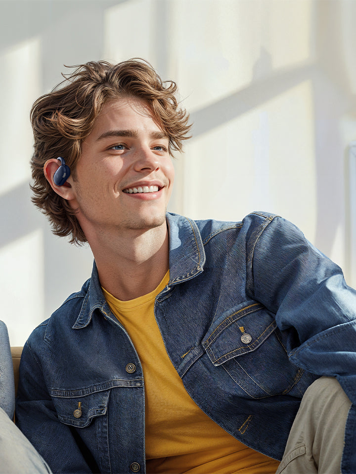 A man wearing denim using blue earbuds.
