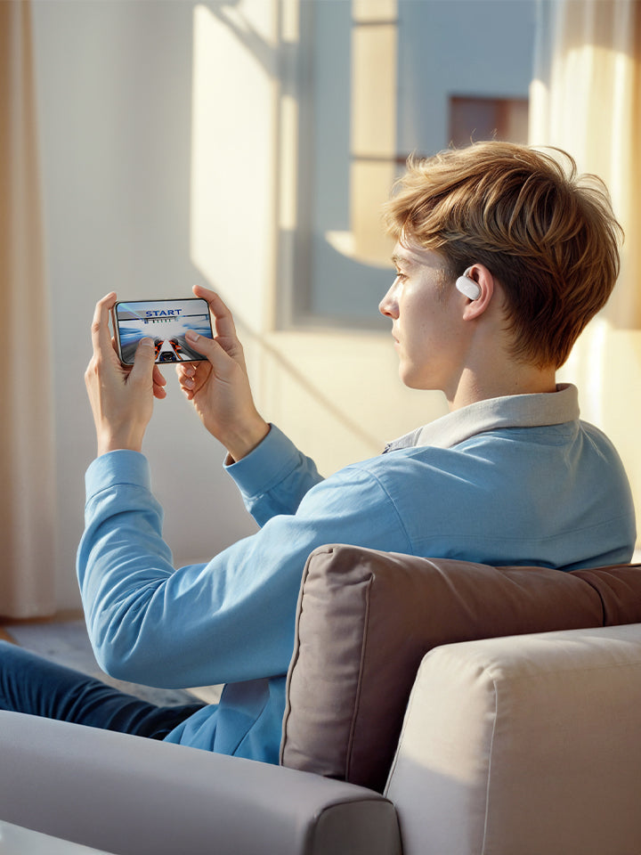 A man playing on his phone wearing white earbuds.