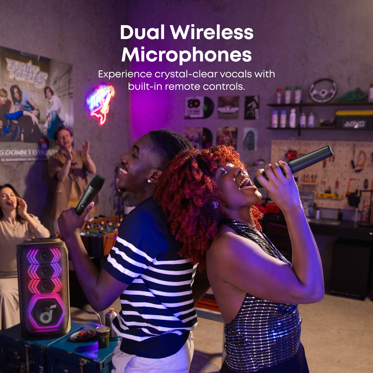 Two people singing with dual wireless microphones in a room with posters and shelves.