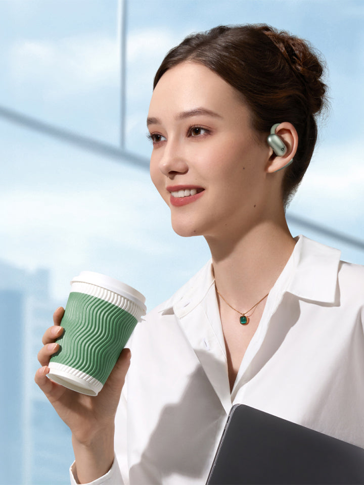 A woman holding a cup wearing green earbuds.